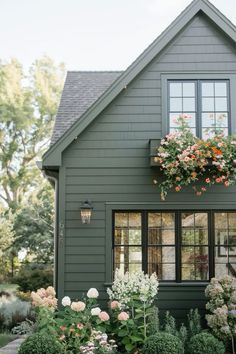 a green house with flowers in the window boxes