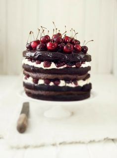 a chocolate cake with cherries and whipped cream