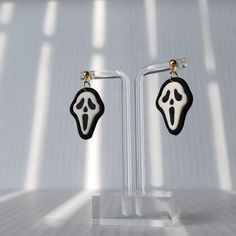 a pair of black and white earrings with a ghost face hanging from it's sides