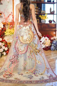 a woman is walking down the runway wearing a dress made out of flowers and feathers