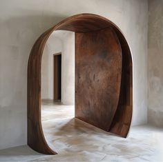 an arch shaped wooden object in the middle of a room with white walls and flooring