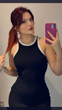 a woman with red hair taking a selfie in front of a mirror wearing a black and white dress