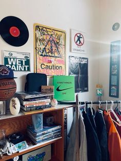 a room filled with lots of clothes and posters on the wall above it is a shelf full of shirts