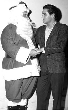 a man in a suit and tie standing next to a person dressed as santa claus