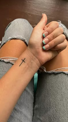 a woman's arm with a cross tattoo on it