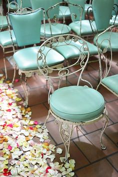 several chairs with flower petals on the floor and one chair has a blue seat cover