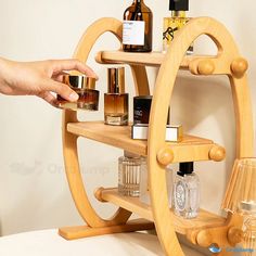 a wooden shelf with several bottles on it and a hand reaching for the top one