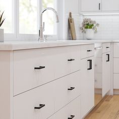 a kitchen with white cabinets and wooden floors