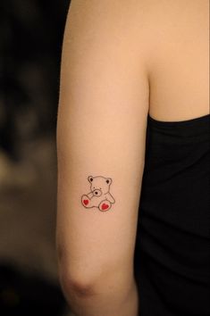 a woman's arm with a small tattoo of a teddy bear and hearts on it