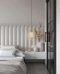 a white bed sitting next to a tall window in a bedroom under a light fixture