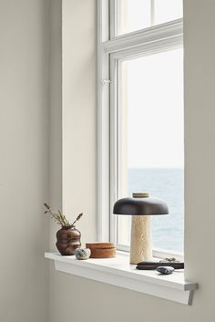 a window sill with a lamp, vase and other items sitting on the ledge