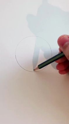 a person holding a pencil in their left hand and drawing on a piece of paper