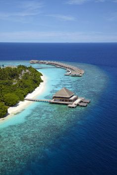 an island in the middle of the ocean with a dock and water villa on it