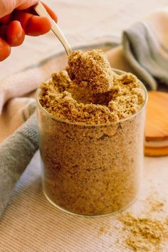 a person is spooning something into a glass jar filled with brown sugar and cinnamon