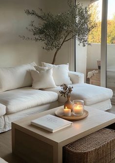 a living room filled with white furniture and a tree in the middle of the room