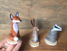 three small stuffed animals sitting on top of each other in front of a person's hand