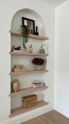 some shelves with vases and pictures on them in a room that has white walls