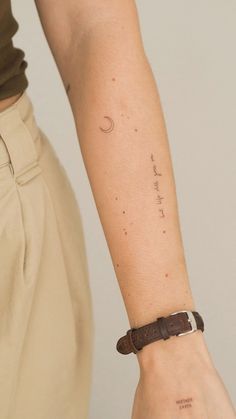 a person's arm with a wristband and a small crescent tattoo on it