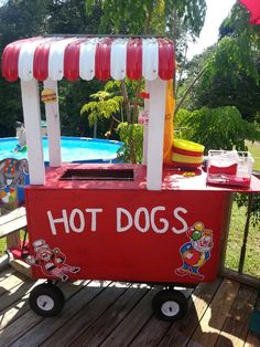 a hot dog cart sitting on top of a wooden deck next to a swimming pool