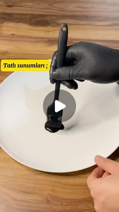 a person holding a brush on top of a white plate with the words tati summari written across it