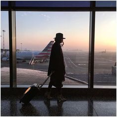 a man walking towards an airport terminal with his luggage in hand and the sun setting behind him