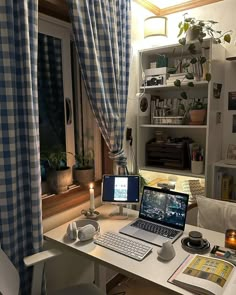 a laptop computer sitting on top of a white desk next to a window with curtains