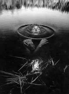 a black and white photo of a person floating in water with their head above the water's surface