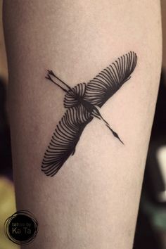 a black and white photo of a bird tattoo on the right thigh, with an arrow in it's center