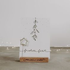 a white card with a wooden stand holding a star and some writing on the front