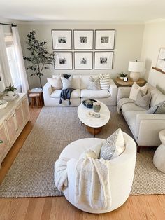 a living room filled with white furniture and pictures on the wall above it's windows