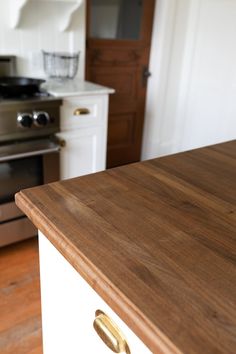 a wooden counter top in a kitchen next to an oven and stove with white cabinets