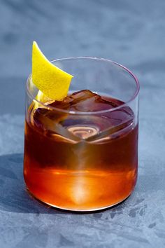 a close up of a drink in a glass with a lemon wedge on the rim