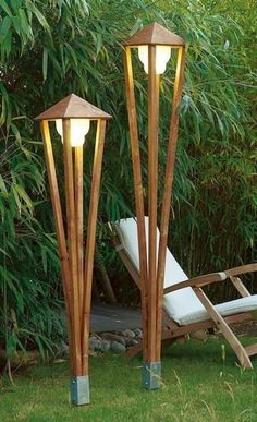 two wooden lamps sitting in the grass next to a lawn chair