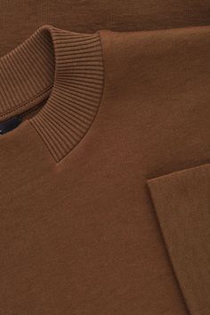 an image of a brown polo shirt that is folded up and showing the front pocket