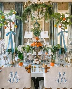 a dining room table decorated with oranges and greenery for an elegant dinner party