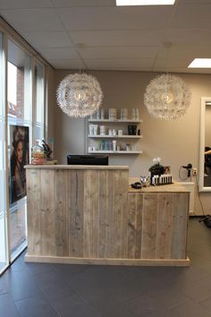 the inside of a hair salon with wooden counter top and hanging chandelier above it