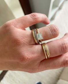 a woman's hand with two gold rings on top of her finger and the other ring