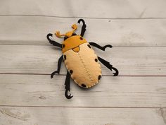 a stuffed animal that looks like a bug on a wooden floor with white boards behind it