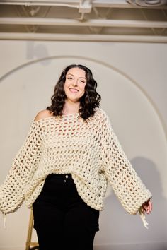 a woman standing in front of a white wall with her hands on her hips and smiling at the camera