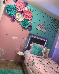 a bedroom decorated in pink, blue and green with flowers on the wall above the bed