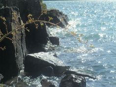 the water is crystal blue and there are rocks in the foreground