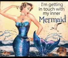 a woman in a blue dress is standing next to a sign with a mermaid on it