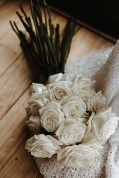 a bouquet of white roses sitting on top of a table next to a piece of cloth