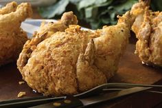 fried chicken on a cutting board with tongs