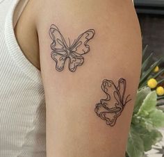 two butterflies tattoo on the back of a woman's left arm, one is black and white