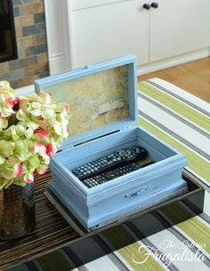 a blue box sitting on top of a table next to a vase filled with flowers