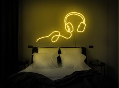 a bed with headphones on it and a neon sign above it that says listen to the music