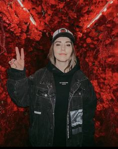 a woman standing in front of a red background with her hand up to the camera