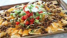 a tray filled with nachos covered in cheese and toppings on top of tortilla chips