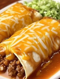 two enchiladas on a plate with lettuce and meat in sauce